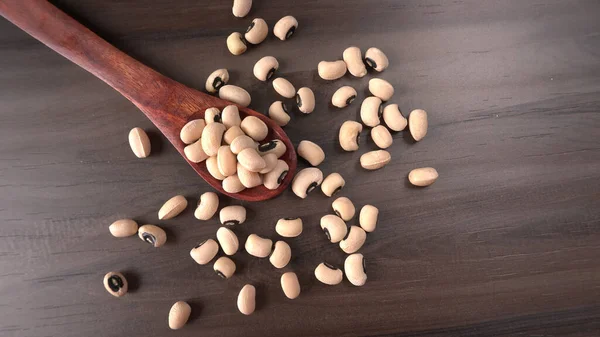 Ahşap kaşıklı pişmemiş siyah bezelyeler. Sağlıklı gıda kavramı.
