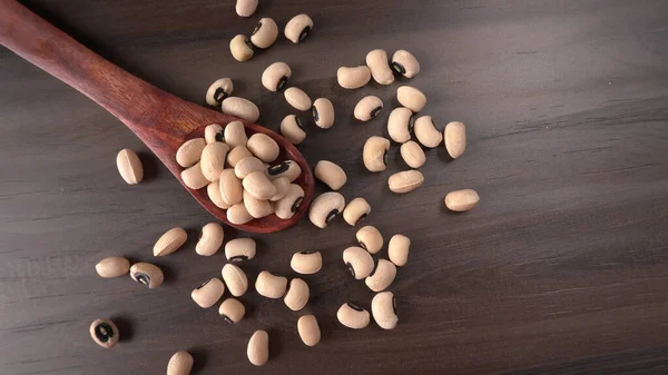 Ahşap kaşıklı pişmemiş siyah bezelyeler. Sağlıklı gıda kavramı.