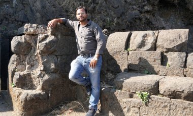 INDIA - 25 ARALIK 2021: Eski bir Hint kalesinde fotoğraf çektirmek için poz veren genç Hintli adam