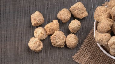 Koyu arkaplanda çiğ soya parçaları. Sağlıklı, besleyici soya fasulyesi, kasede parçalar. Vejetaryen gıda konsepti.