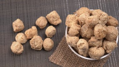 Ahşap arka planda çiğ soya parçaları. Sağlıklı, besleyici soya fasulyesi, kasede parçalar. Vejetaryen gıda konsepti.