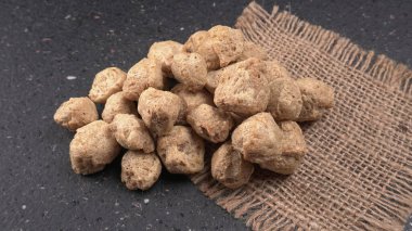 Koyu arkaplanda çiğ soya parçaları. Sağlıklı, besleyici soya fasulyesi, kasede parçalar. Vejetaryen gıda konsepti.