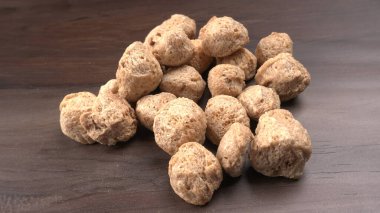 Ahşap arka planda çiğ soya parçaları. Sağlıklı, besleyici soya fasulyesi, kasede parçalar. Vejetaryen gıda konsepti.