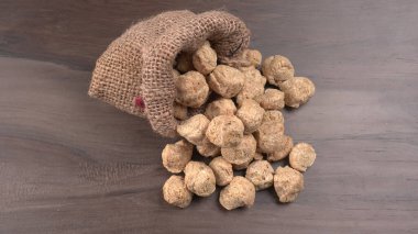 Ahşap arka planda bir çuval çiğ soya. Sağlıklı, besleyici soya fasulyesi, kasede parçalar. Vejetaryen gıda konsepti.