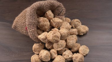 Ahşap arka planda bir çuval çiğ soya. Sağlıklı, besleyici soya fasulyesi, kasede parçalar. Vejetaryen gıda konsepti.