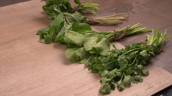 Fresh greens on wooden background. Green sorrel, mint and parsley on wooden background