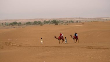 INDIA - 08 AĞUSTOS 2019: Gündüz vakti Hindistan çölünde deveye binen turistler 