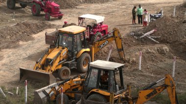 INDIA - 24 Ocak 2022: inşaat tarafında taş ve zemin taşıyan traktörlerdeki işçiler. Hava görünümü.