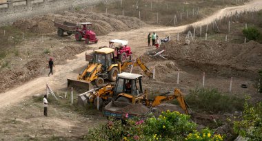 INDIA - 24 Ocak 2022: inşaat tarafında taş ve zemin taşıyan traktörlerdeki işçiler. Hava görünümü.