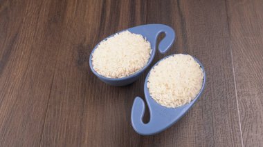 Tahta masada, plastik mavi kaselerde çiğ pirinç, sağlıklı yiyecekler. Boşluğu kopyala.