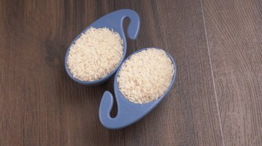 Tahta masada, plastik mavi kaselerde çiğ pirinç, sağlıklı yiyecekler. Boşluğu kopyala.