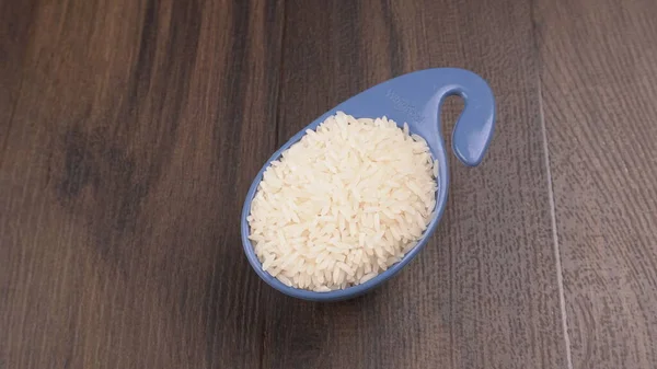 Raw rice in plastic blue bowl on wooden table, Healthy food. Copy space.