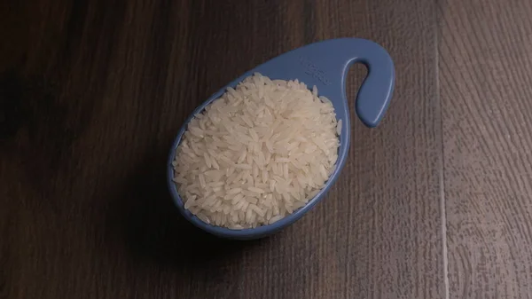 Raw rice in plastic blue bowl on wooden table, Healthy food. Copy space.