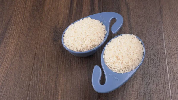 Raw rice in plastic blue bowls on wooden table, Healthy food. Copy space.