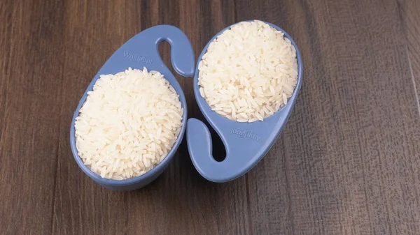 Raw rice in plastic blue bowls on wooden table, Healthy food. Copy space.