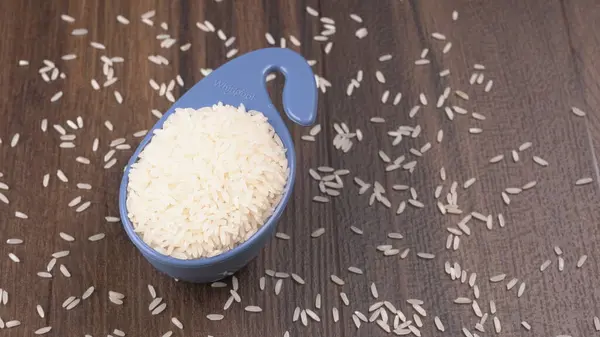 Raw rice in plastic blue bowl on wooden table, Healthy food. Copy space.