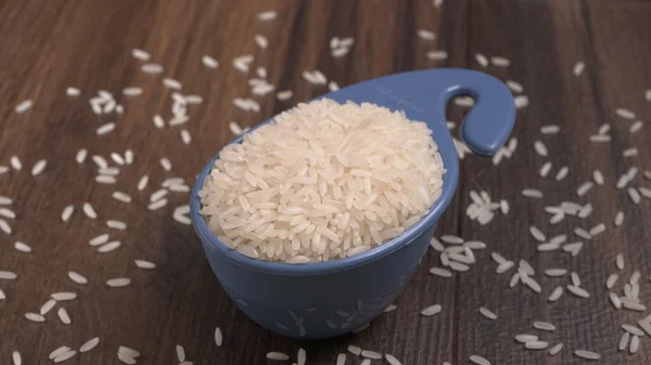 Raw rice in plastic blue bowl on wooden table, Healthy food. Copy space.