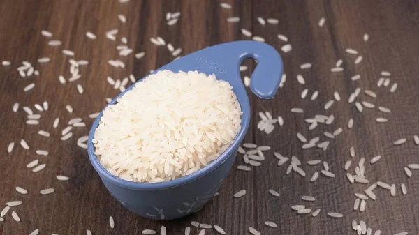 Raw rice in plastic blue bowl on wooden table, Healthy food. Copy space.