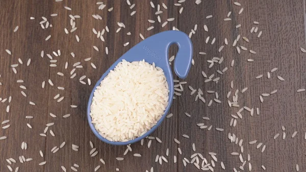 Raw rice in plastic blue bowl on wooden table, Healthy food. Copy space.