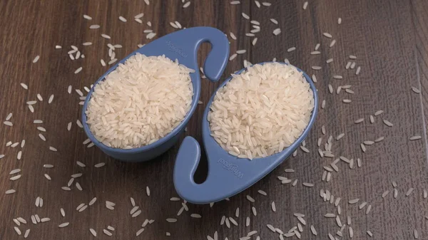 Raw rice in plastic blue bowls on wooden table, Healthy food. Copy space.