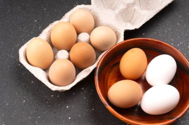 Karton kutu ve arka planda taze tavuk yumurtaları olan ahşap kase. 