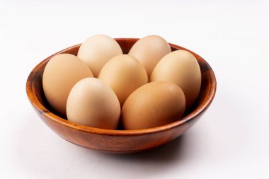 Beyaz arka planda taze tavuk yumurtası olan ahşap kase, yakın plan. 