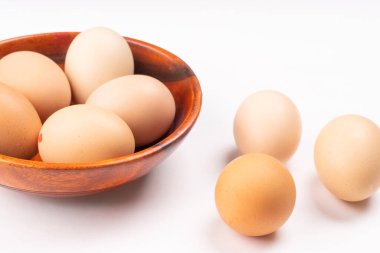 Beyaz arka planda taze tavuk yumurtası olan ahşap kase, yakın plan. 