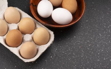 Koyu ahşap arka planda çiğ yumurta ve kutu.