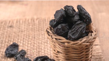 Tahta masanın üzerinde kurumuş siyah hurmalardan oluşan hasır sepetin yakınına.
