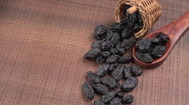 Hasır sepet ve ahşap masada kurumuş siyah hurmalar.