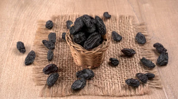 Nahaufnahme Von Weidenkorb Mit Getrockneten Schwarzen Datteln Auf Holztisch — Stockfoto