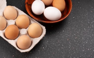 Koyu ahşap arka planda çiğ yumurta ve kutu.