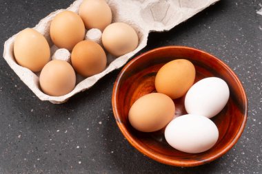 Koyu ahşap arka planda çiğ yumurta ve kutu.