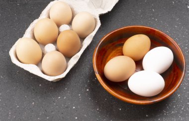 Koyu ahşap arka planda çiğ yumurta ve kutu.