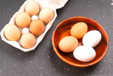 Koyu ahşap arka planda çiğ yumurta ve kutu.