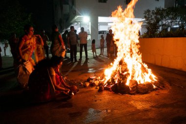 INDIA - 17. Mart 2022: Hindu dindarlar, Holi 'nin bahar bayramı arifesinde Holika Dahan sırasında şenlik ateşi etrafında kutsal ayinler düzenlerler.