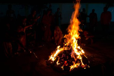 INDIA - 17. Mart 2022: Hindu dindarlar, Holi 'nin bahar bayramı arifesinde Holika Dahan sırasında şenlik ateşi etrafında kutsal ayinler düzenlerler.