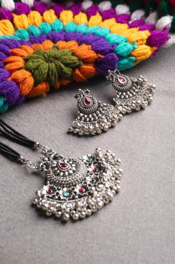 Geleneksel Hint antikası ya da gri arka planda küpeleri olan retro tarzı kolye 