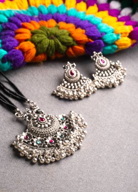 Geleneksel Hint antikası ya da gri arka planda küpeleri olan retro tarzı kolye 