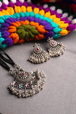 Geleneksel Hint antikası ya da gri arka planda küpeleri olan retro tarzı kolye 