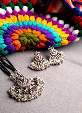 Geleneksel Hint antikası ya da gri arka planda küpeleri olan retro tarzı kolye 