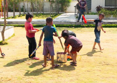 INDIA - 18 Mart 2022: Çocuklar gündüz vakti bahçede su tabancalarıyla oynuyorlar 