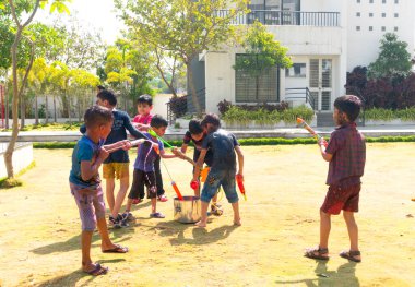 INDIA - 18 Mart 2022: Çocuklar gündüz vakti bahçede su tabancalarıyla oynuyorlar 