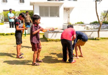 INDIA - 18 Mart 2022: Çocuklar gündüz vakti bahçede su tabancalarıyla oynuyorlar 