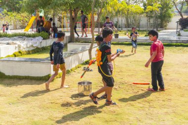 INDIA - 18 Mart 2022: Çocuklar gündüz vakti bahçede su tabancalarıyla oynuyorlar 