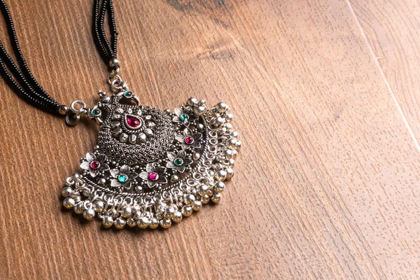 Geleneksel Hint antikası ya da tahta arka planda küpeleri olan retro tarzı kolye 