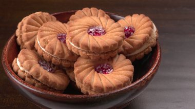 Bir kase tatlı reçelli bisküvi. Sandviç bisküvileri veya ahşap arka planda kremalı bisküviler. 