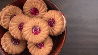 Bir kase tatlı reçelli bisküvi. Sandviç bisküvileri veya ahşap arka planda kremalı bisküviler. 