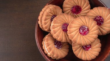 Bir kase tatlı reçelli bisküvi. Sandviç bisküvileri veya ahşap arka planda kremalı bisküviler. 