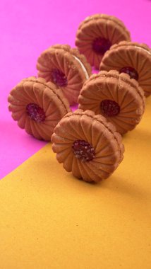 Tatlı reçelli bisküvi yığını. Sandviç bisküvileri veya pembe-sarı arka planda kremalı bisküviler. 